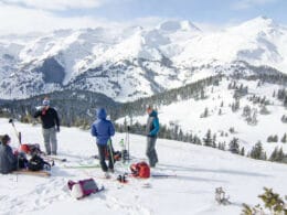 Image of skiers and snowboarders enjoying a drink at the top of Bluebird Backcountry in Colorado