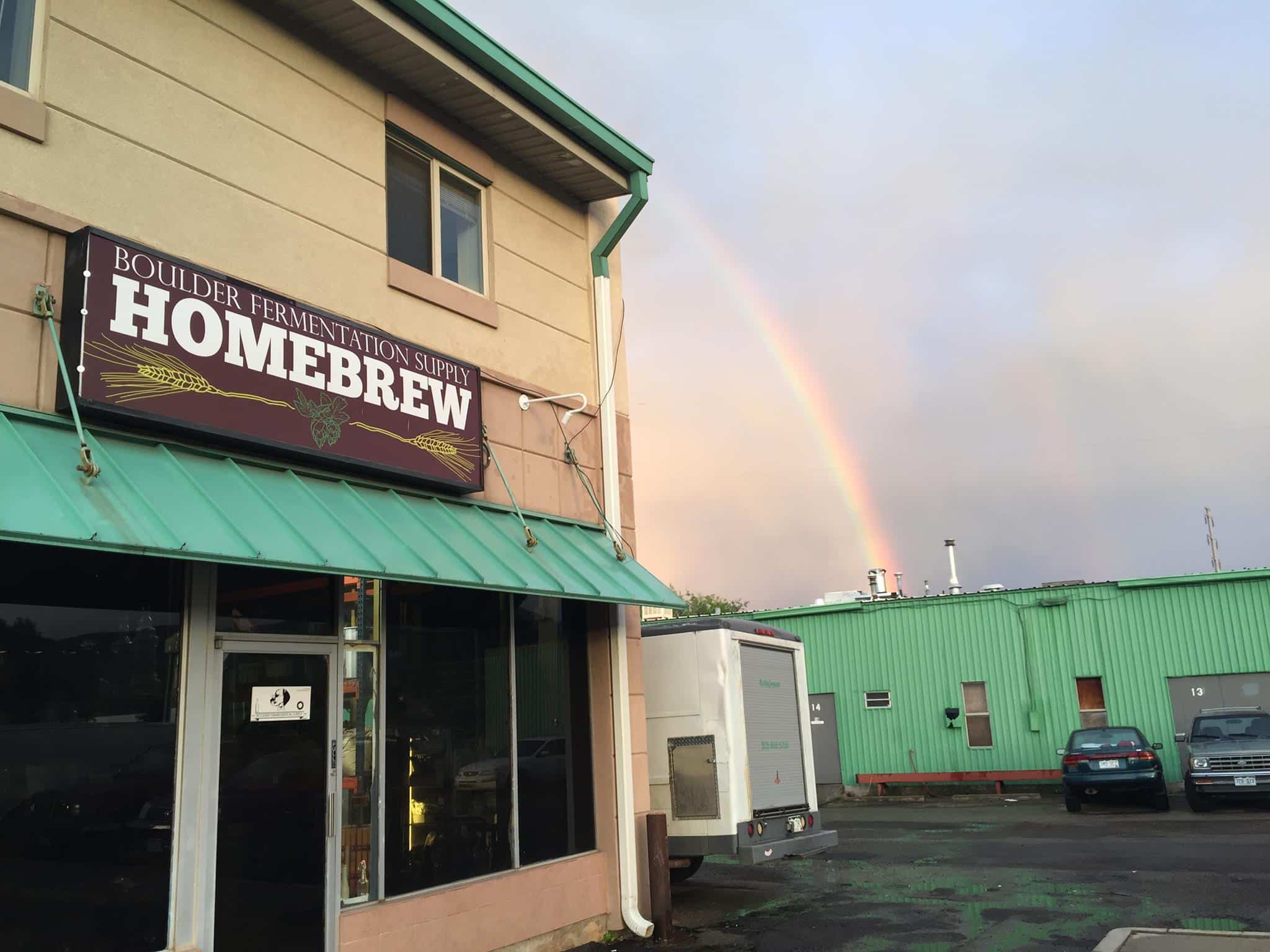 Rainbow in a grey sky with the entrance to Boulder Fermentation Supply Homebrew store