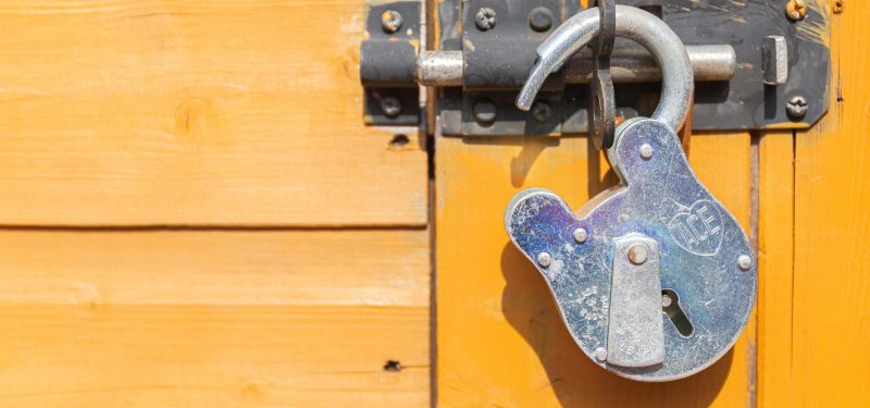 Unlocked padlock securing a latch on a yellow door