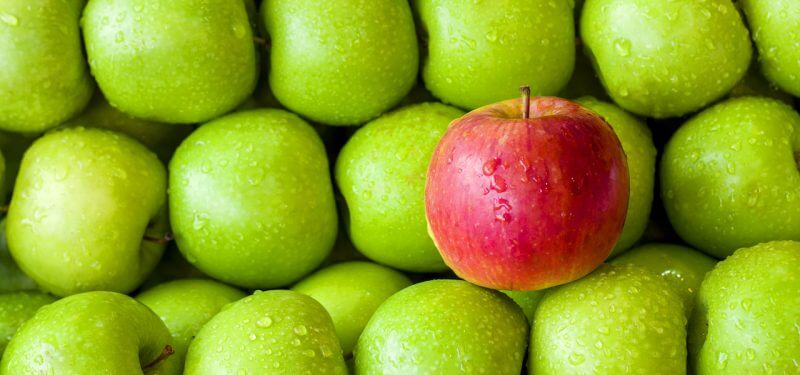 A red apple with green apples in the background