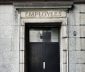 Photo of black wooden door in stone wall with employees craved into the lintal above door