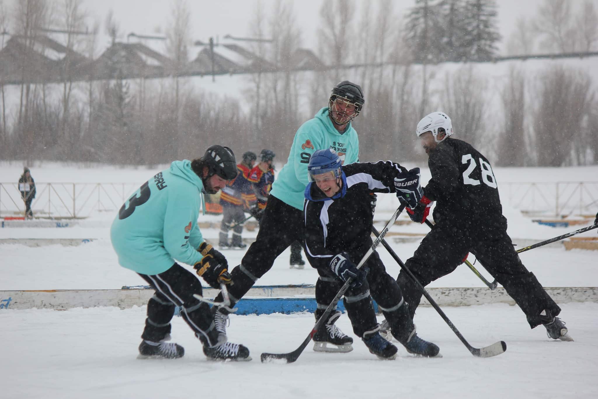 4 people playing ice hockey on a pond