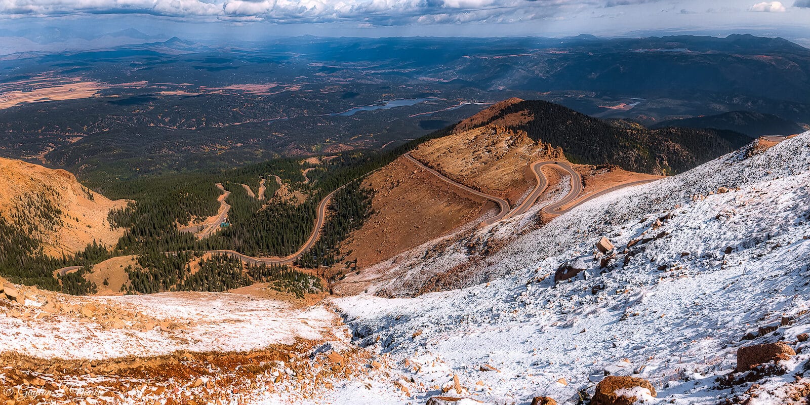 Overlooking snow on Pikes Peak with view of highway switchbacks in distance