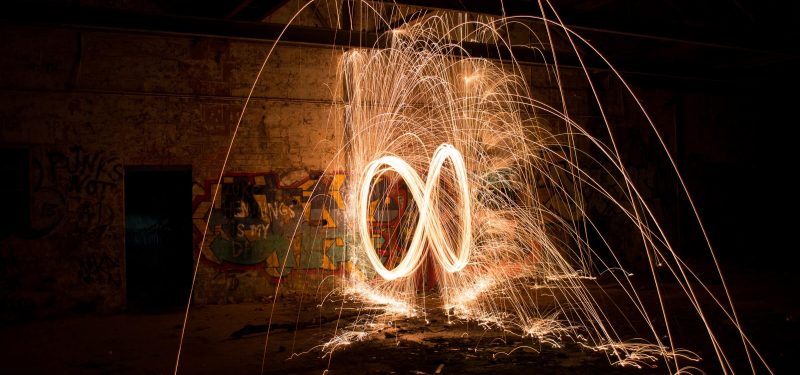 Long exposure nightime photograph of burning steel wool swung in an infinity pattern