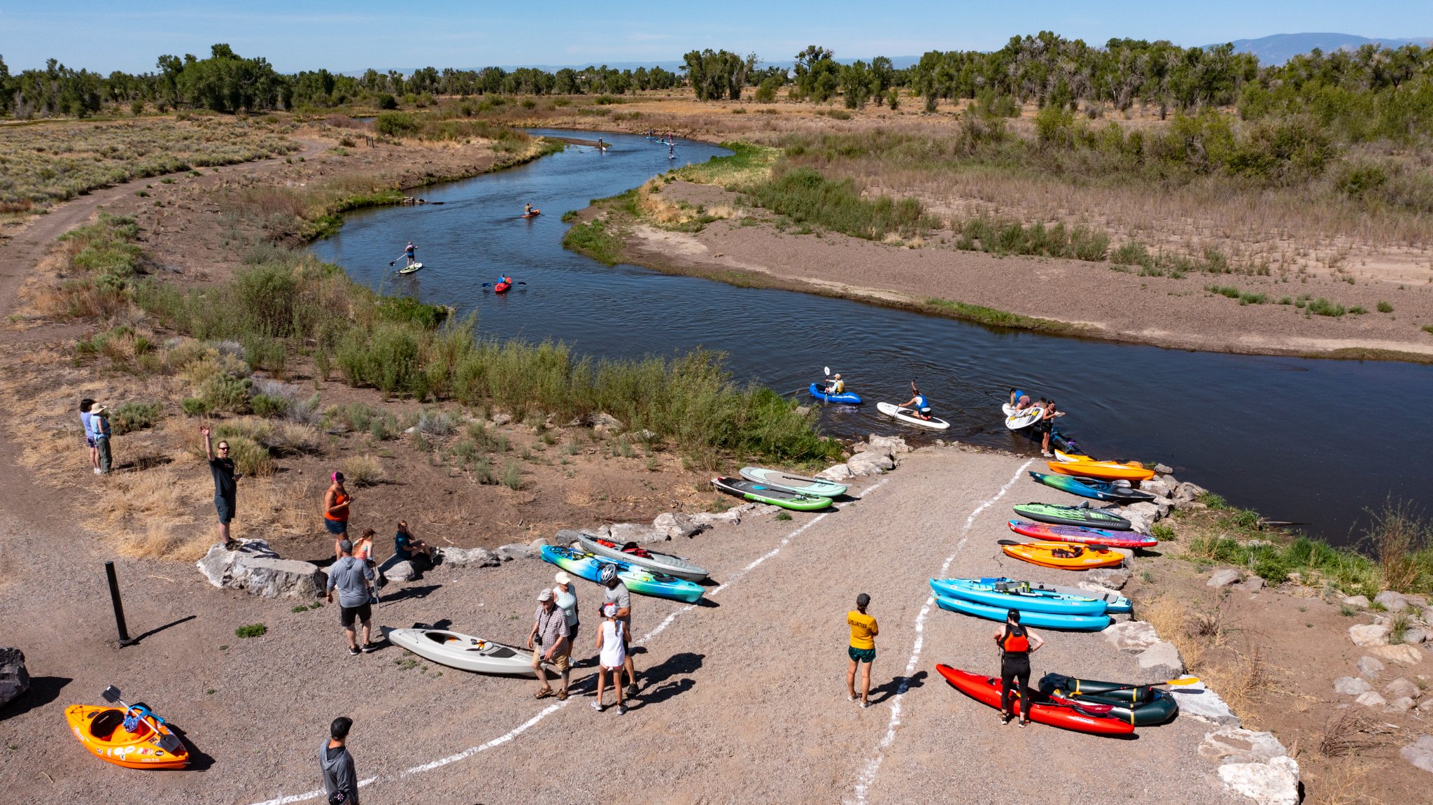 Riverbank with several kayaks as part of the Rio Trio paddle section of the race. 