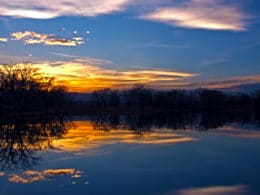 Image of the sunset reflecting on the water at at Riverbend Ponds Natural Area in Fort Collins, Colorado